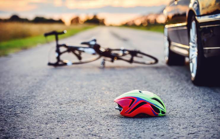 traffic accident between a car and a bicycle with helmet in road